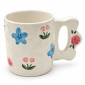 Cream ceramic mug with blue and pink floral details and sculpted handle